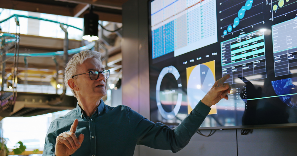 man pointing at screen with charts